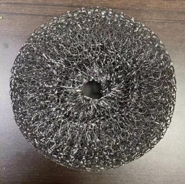 Black mesh scrubber pad with circular shape on dark wooden surface